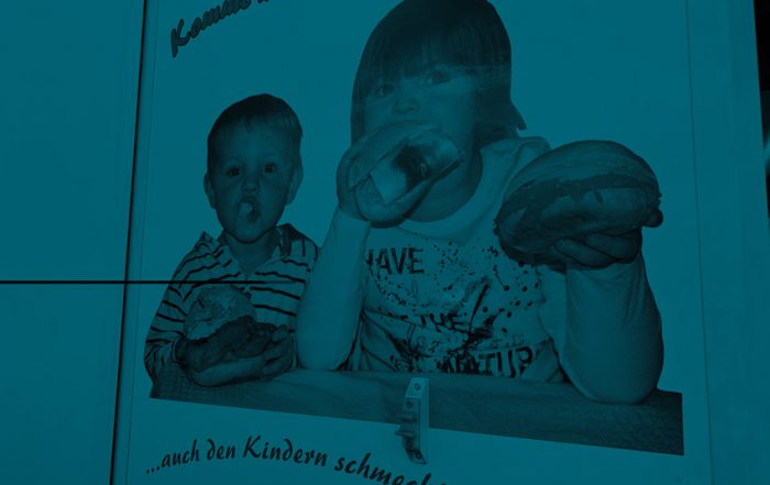 Fahrzeugbeschriftung zeigt Foto, wie zwei Kinder in Fischbrötchen beißen. Die Darstellung ist bizarr, das Foto wirk amateurhaft.