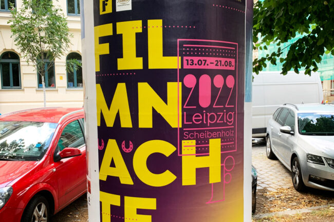 Litfasssäule mit Plakat. Der Text "Fimnächte" ist sinnlos umgebrochen und dadurch nicht leesabar.