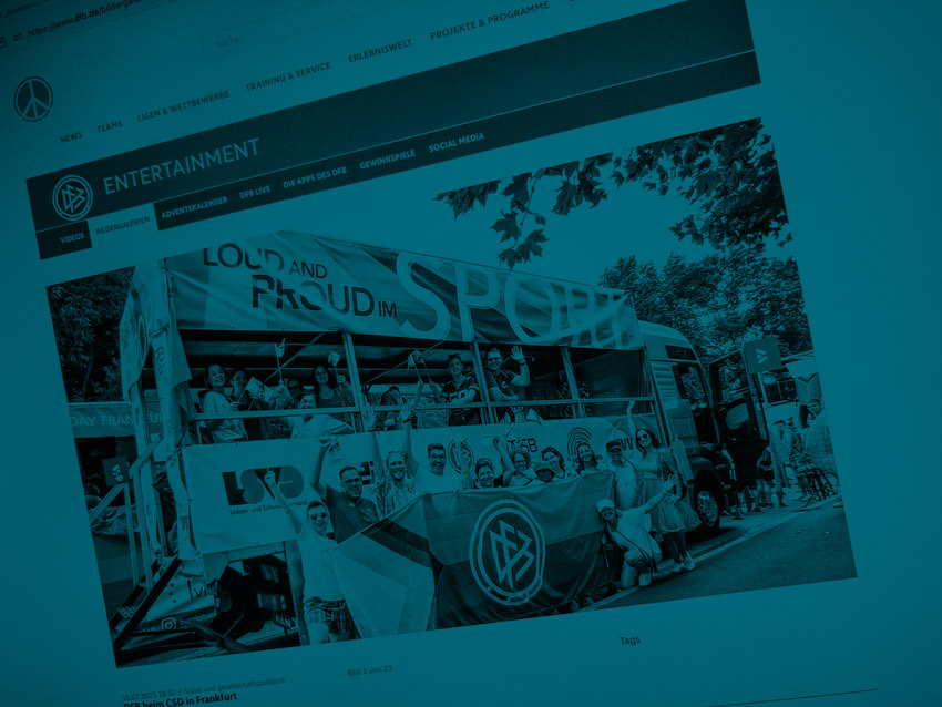 Screenshot Seite DFB: CSD-Wagen für den DFB und LSVD. Die Abbildung zeigt einen LKW mit bunten Bannern mit der Aufschrift "loud and proud im Sport", das Foto ist blau eingefärbt